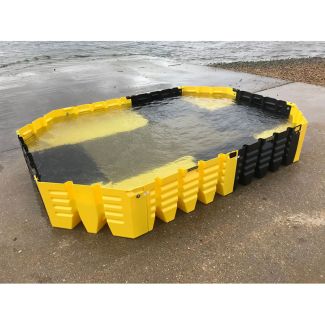 Modular yellow and black flood barrier system fully assembled and filled with water on a concrete coastal ramp